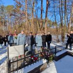 637873524_931740502534805_2886850375782094031_n Grupa ludzi w mundurach szaro-niebieskich składa kwiaty na pomniku w zimowym lesie. Na ziemi leży śnieg, a tło tworzą drzewa. Kilka osób robi zdjęcia i trzyma flagi.