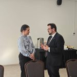 653581078_951497330559122_2674801212625356822_n Na zdjęciu widać mężczyznę i kobietę w rozmowie w jasnym pomieszczeniu. Ona nosi jasnoniebieską bluzkę, on ciemny garnitur. W tle stolik z kawą i przekąskami.