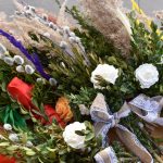 Bukiet z białymi kwiatami, zielenią i kolorowymi wstążkami na drewnianym tle. Żywe kolory dodają energii. Dekoracyjna wstążka z koronki.