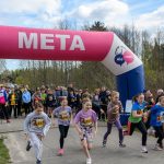 Zdjęcie przedstawia grupę dzieci rozpoczynającą bieg pod różowym napisem „META”. Tło to las i widzowie. Niebiesko-białe elementy widać na nadmuchiwanej bramie.