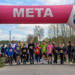 Grupa dzieci stoi na starcie wyścigu pod różowo-białym balonem z napisem META. W tle drzewa i niebo. Po lewej stoper pokazuje 0:00:00.