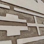 rg1as2aY Ściana z geometrycznym wzorem w kolorach beżu i bieli. Struktura jest trójwymiarowa, z wystającymi prostokątami. Tło jasnobeżowe.