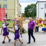 Na zdjęciu widoczna jest procesja z figurą zbożowego krzyża. Osoby w strojach ludowych niosą dekoracje kwiatowe. Piękny, słoneczny dzień.