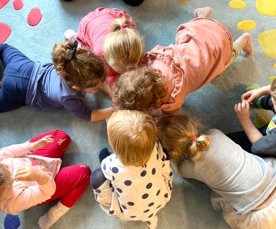 Kilkoro dzieci bawiących się w kółku na podłodze.
